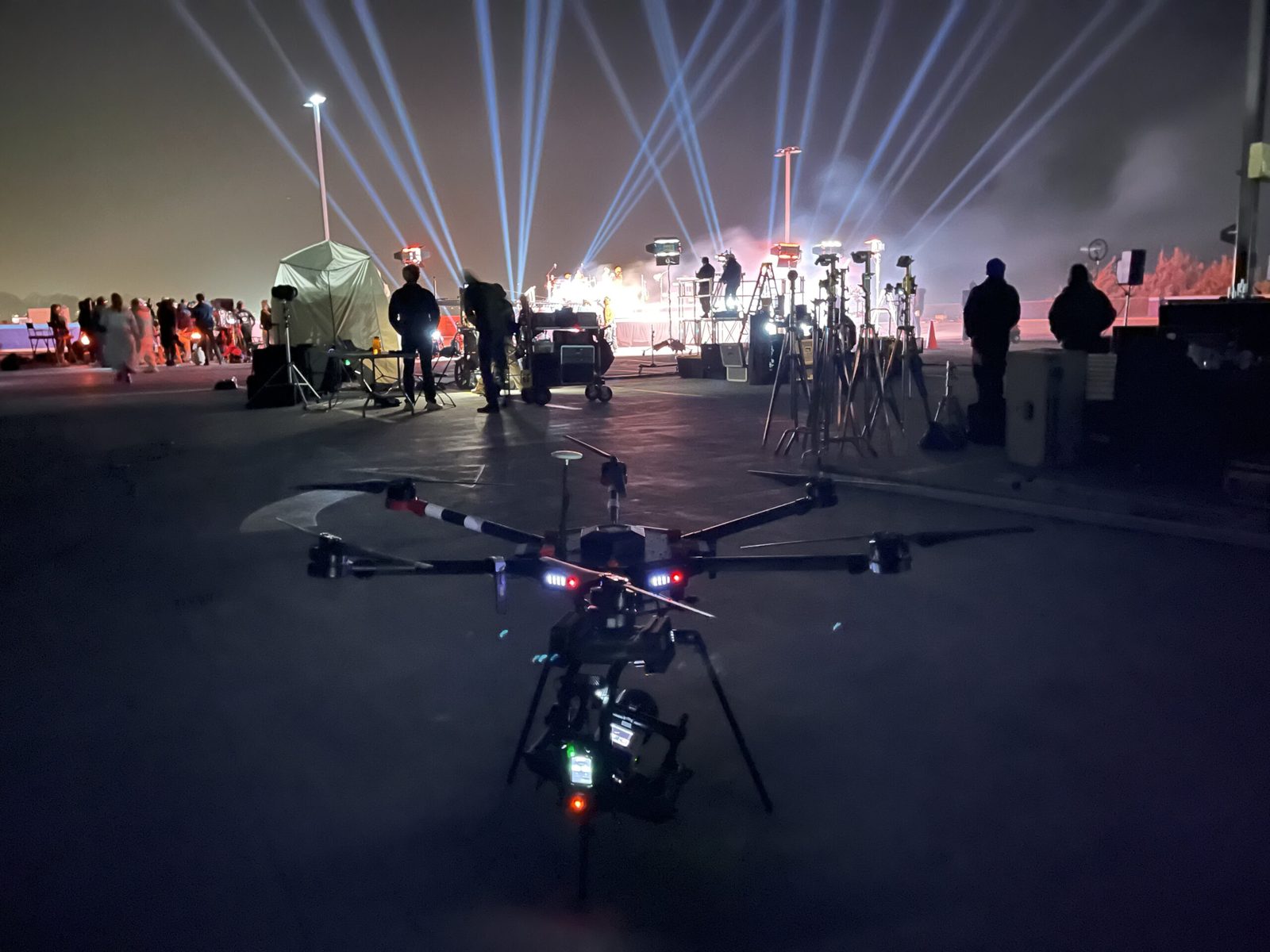 Camera drone on the ground at a concert, stage lights and beams behind it