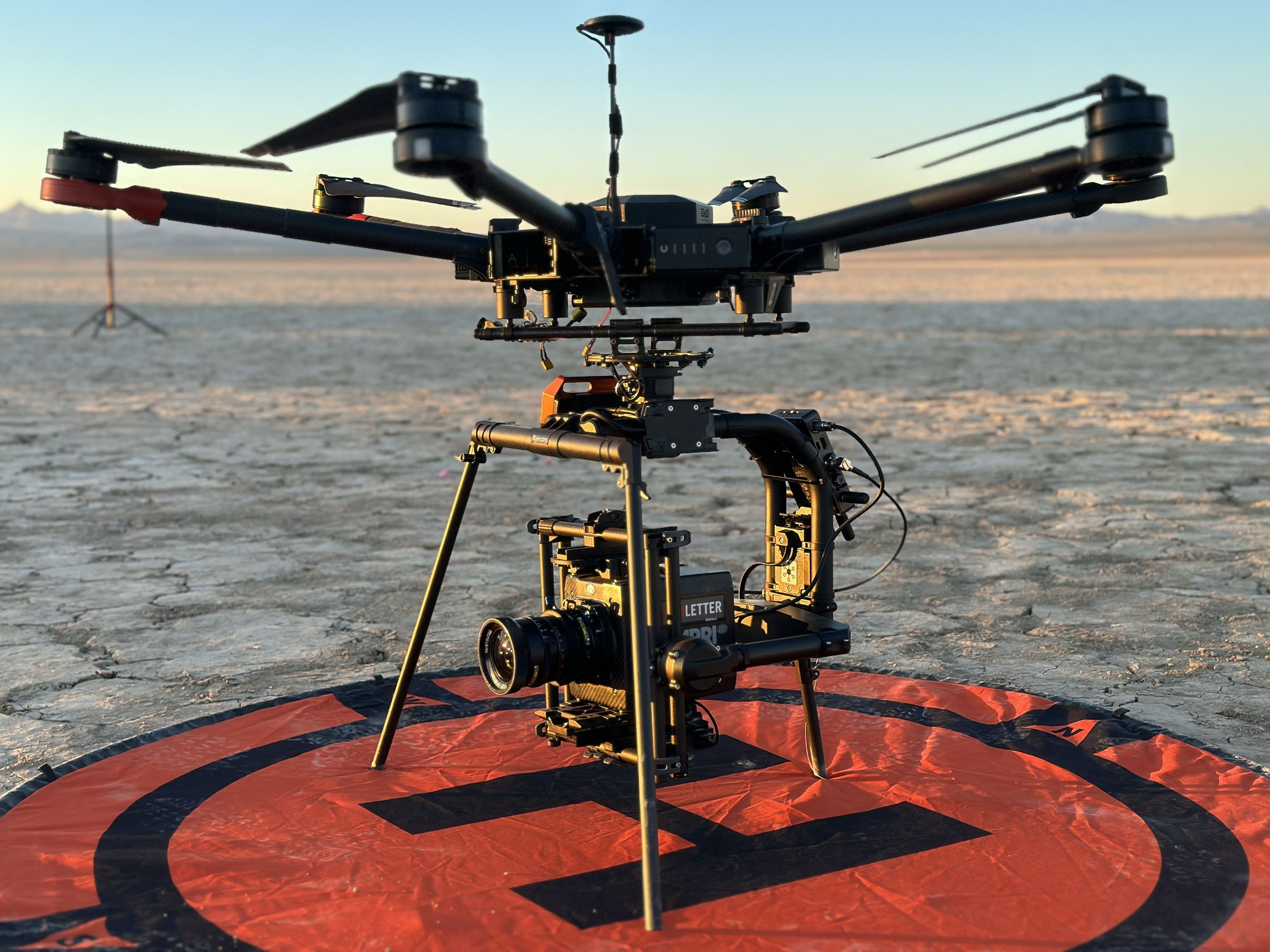 Heavy-lift drone carrying a cinema camera on a dry lake bed landing pad