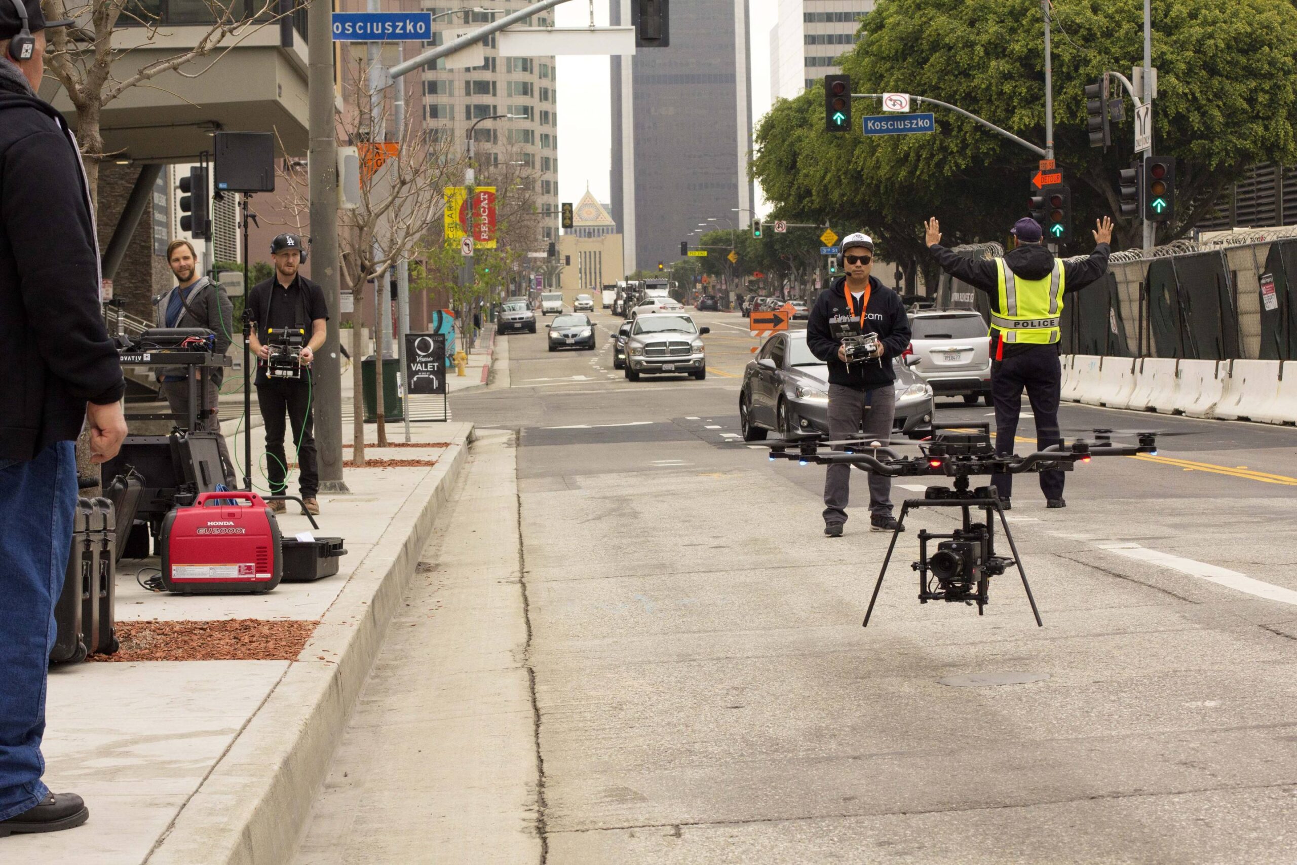 Crew flying a camera drone on a city street, fire truck and crew behind