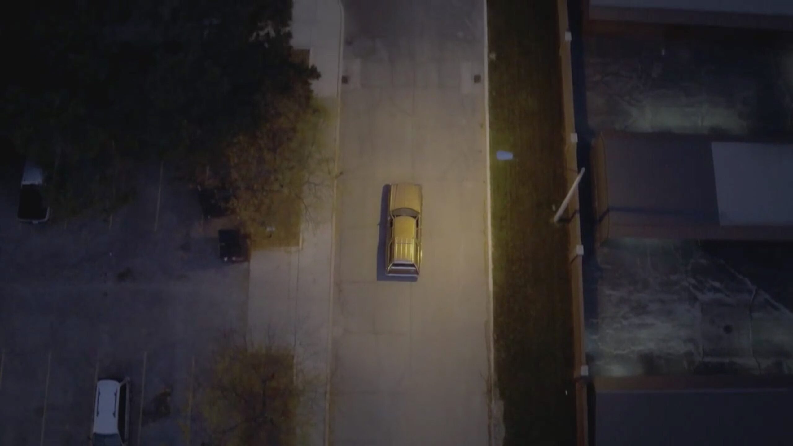 Yellow car on a road at night, viewed straight down